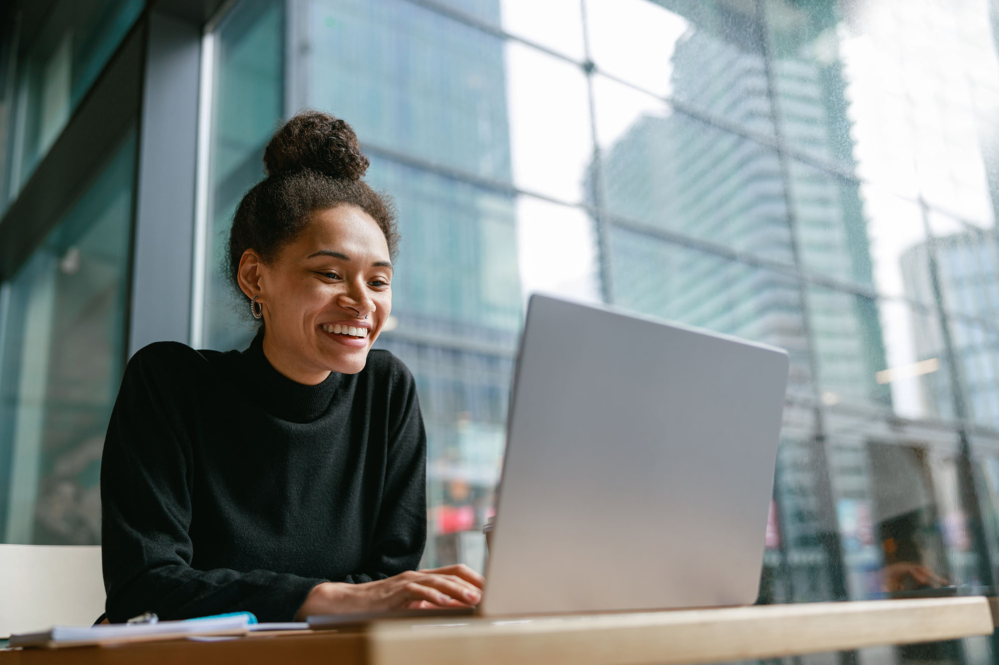 A smiling woman sat at a laptop alone