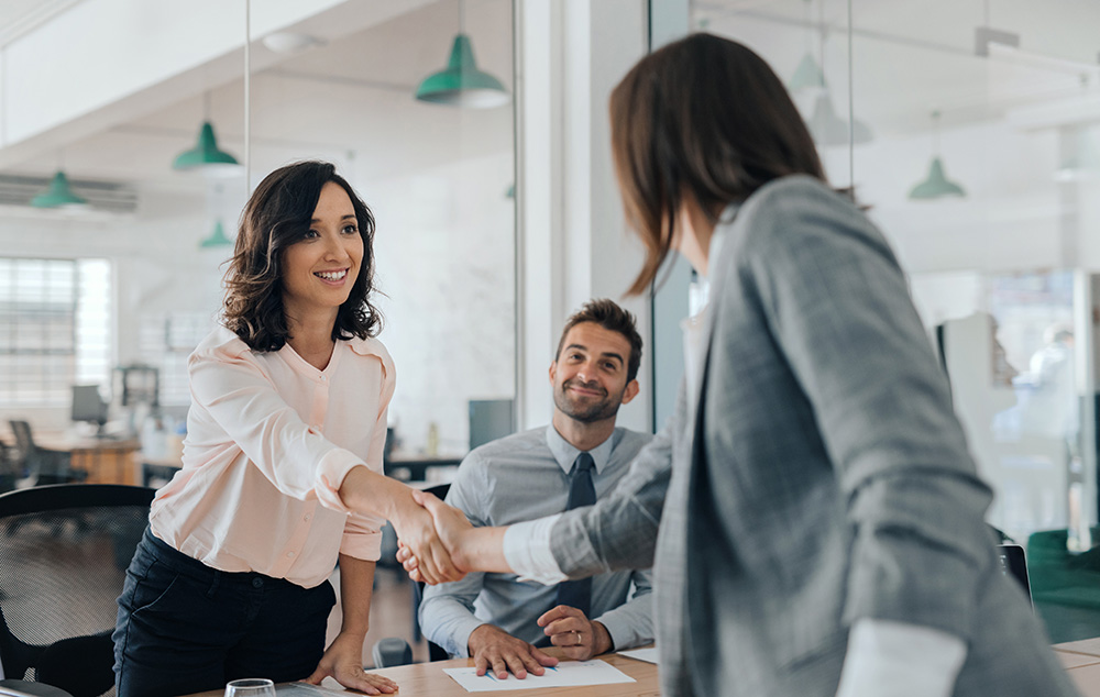 A formal business meeting with two women shaking hands